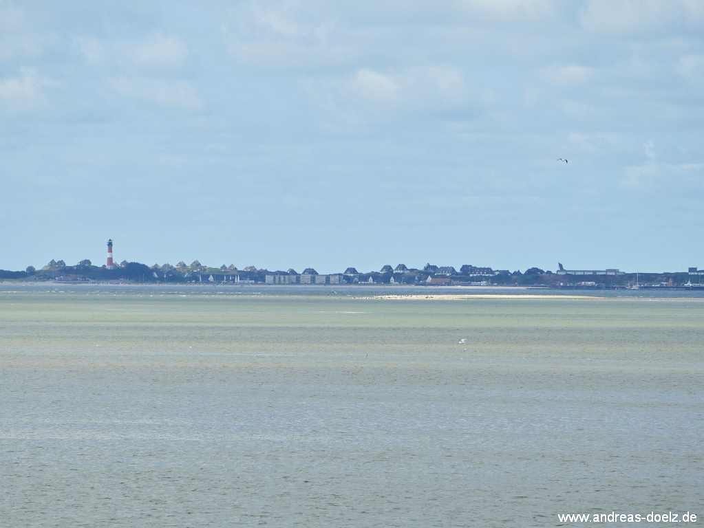 Wattwanderung zur Kormoraninsel von Amrum aus:  Nachdem die Flut wieder eingesetzt hat, ist die Kormoraninsel vom Deich bei Dunsum auf F&ouml;hr als hellbraunes Band vor Sylt im Hintergrund zu erkennen.